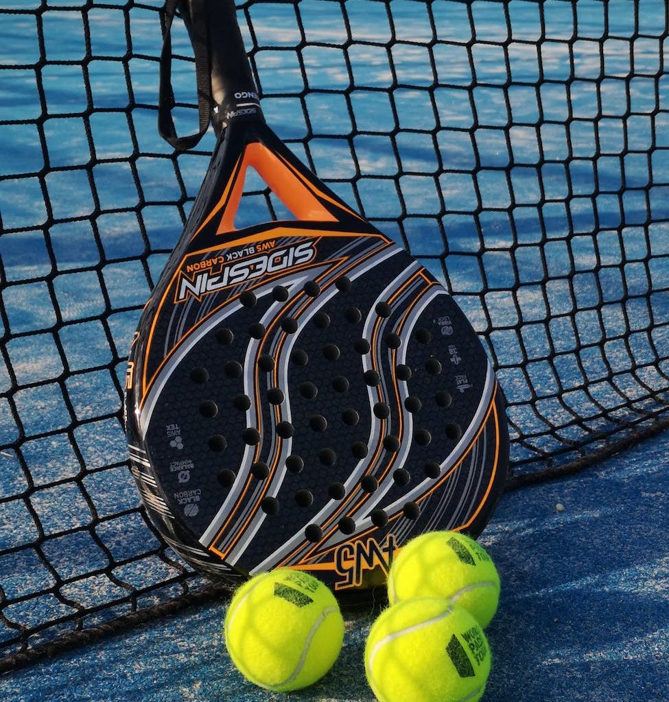 padel racket and bright balls on tennis court