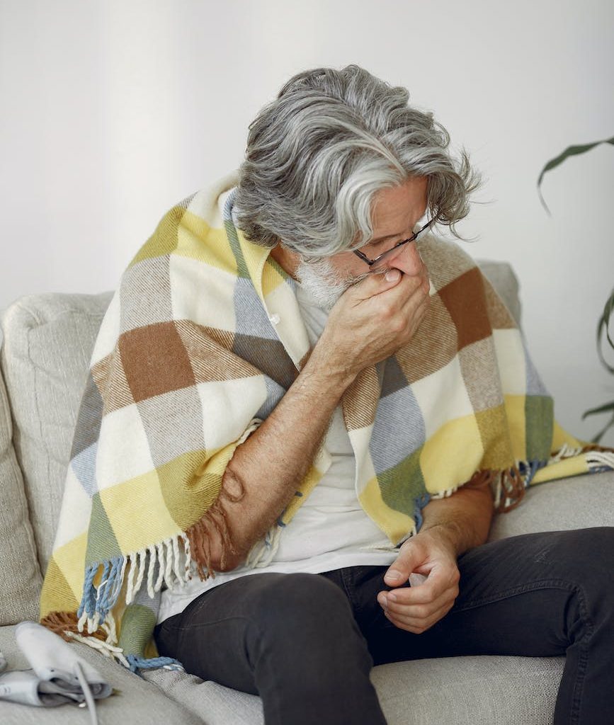 a man sitting on a sofa and coughing