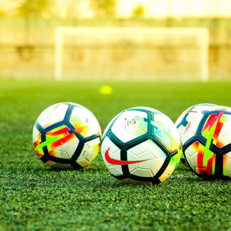 three white-and-black soccer balls on field