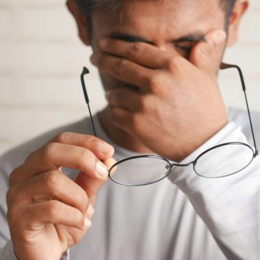 a man holding a pair of glasses up to his face