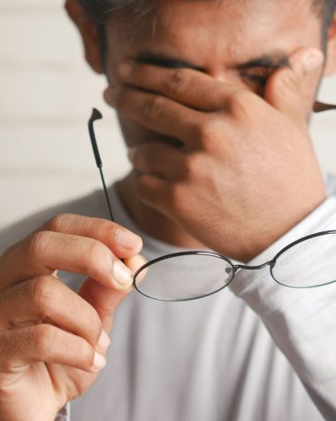 a man holding a pair of glasses up to his face