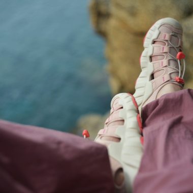 Person's feet in hiking shoes on a cliff overlooking ocean