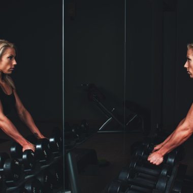 Diverse fitness gadgets voor thuis, waaronder een smartwatch, weerstandsbanden en een hartslagmeter op een houten vloer