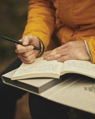 Persoon schrijft zijn trainingsschema op in een notitieboek naast een smartphone